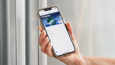 Person holding up smart phone to stainless steel refrigerator door with the Home Connect app on screen.