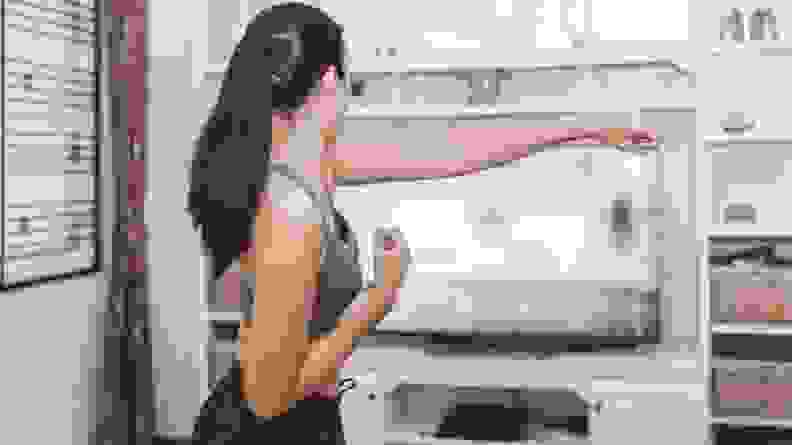 A woman shadow boxing in front of her TV.