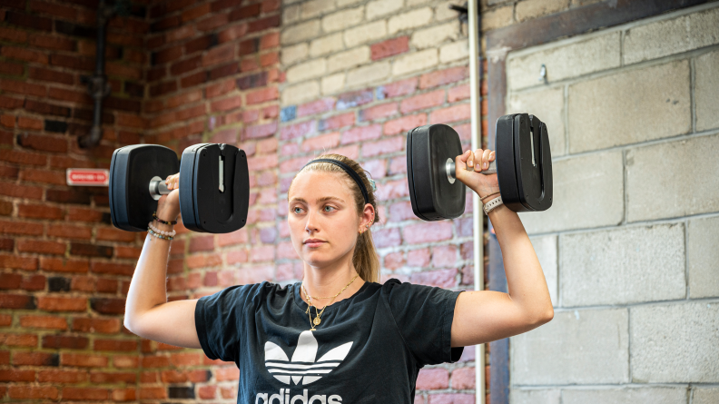 A woman lifting weights with the dumbbells.