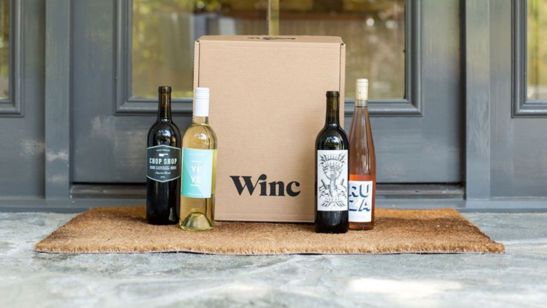 An image of a Winc subscription box on a porch with four bottles of wine laid out beside it.