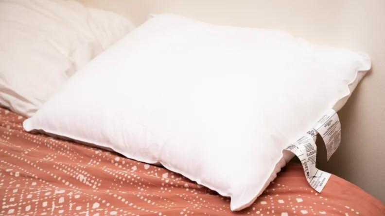 A white pillow sitting at the head of a bed.