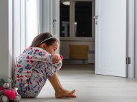 Little girl crouched in hallway with stuffed animal