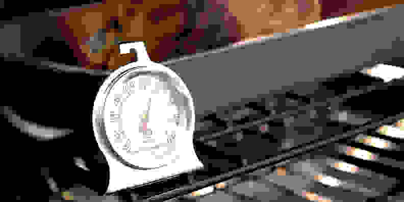 An oven thermometer on a rack in the oven