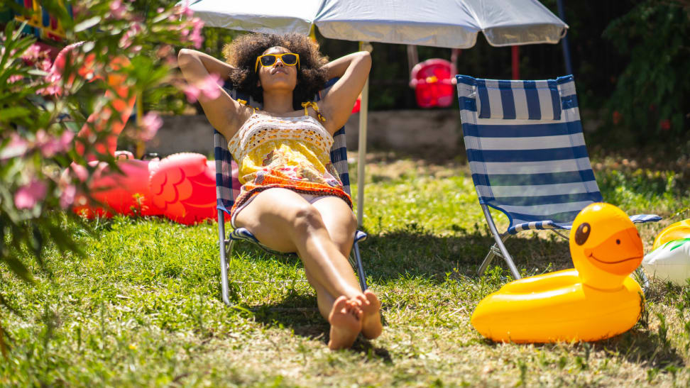 Woman in beach chair relaxing in the sun in her yard next to a duck pool float