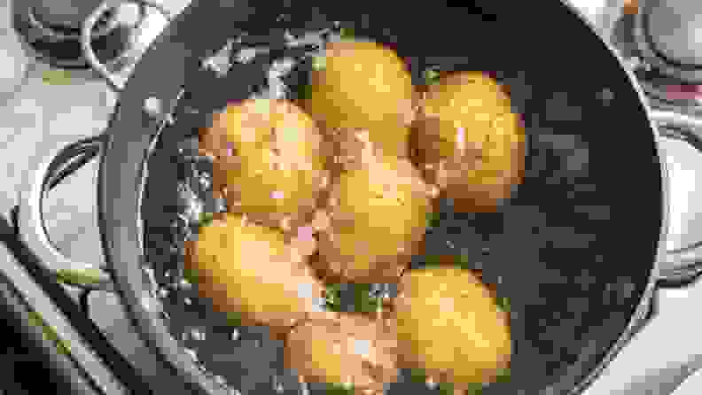 Several potatoes in a pot of boiling water