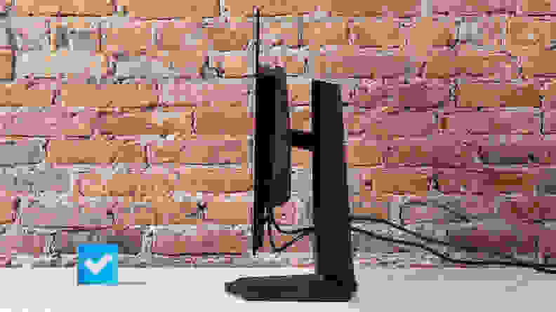 A side view of the MSI MPG 321URX computer on a white desktop with a brick background.