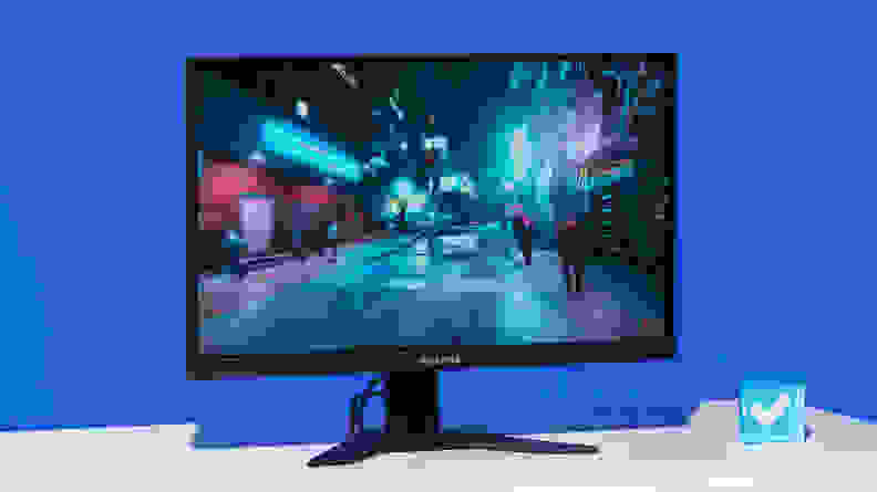 A large computer monitor standing upright on a white desk aganist a blue background.