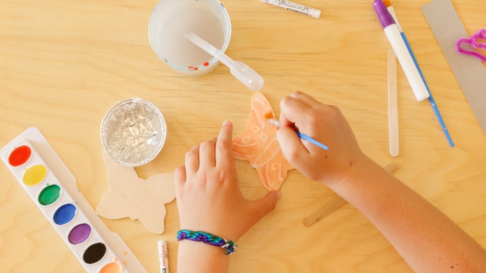 Girl painting wooden butterfly