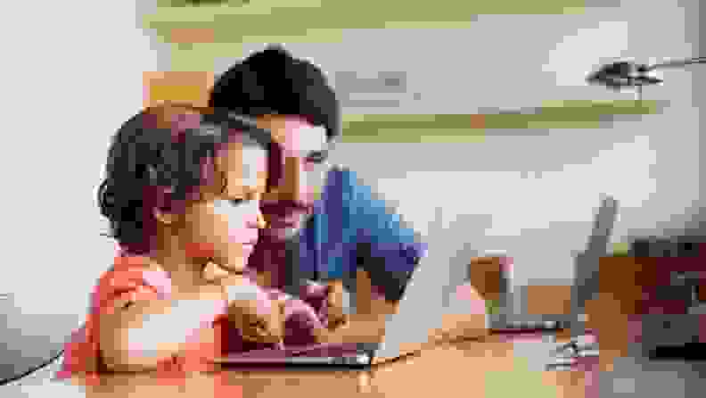 A parent and a child browsing on a laptop.