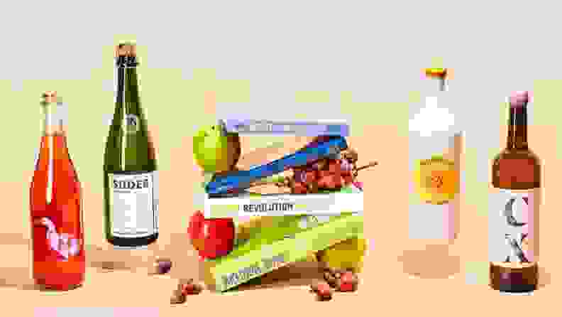 Assorted wine bottles and fruits with stack of books in center.