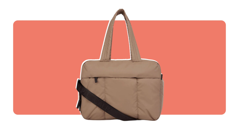 A puffer Calpak Luka Duffel in tan color with crossbody strap and top handle for carrying.