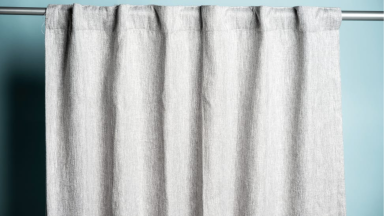 A set of gray curtains hanging from a rod against a blue background