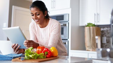 Woman looking at ipad with vegetables