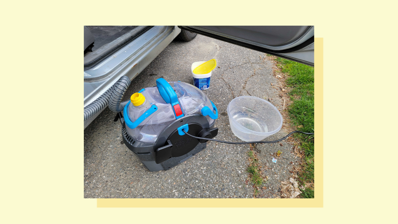 A stain removing device sits outside of a car.