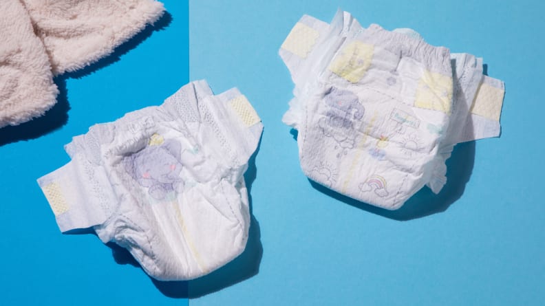 Two Pampers Swaddlers diapers sitting side by side next to a fuzzy blanket.