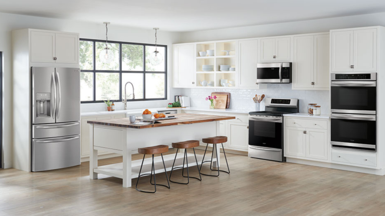 An open, white kitchen with a stainless steel Frigidaire Gallery FG4H2272UF on the left.