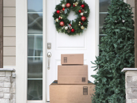 Stack of boxes sitting on a front porch decorated for the holidays.