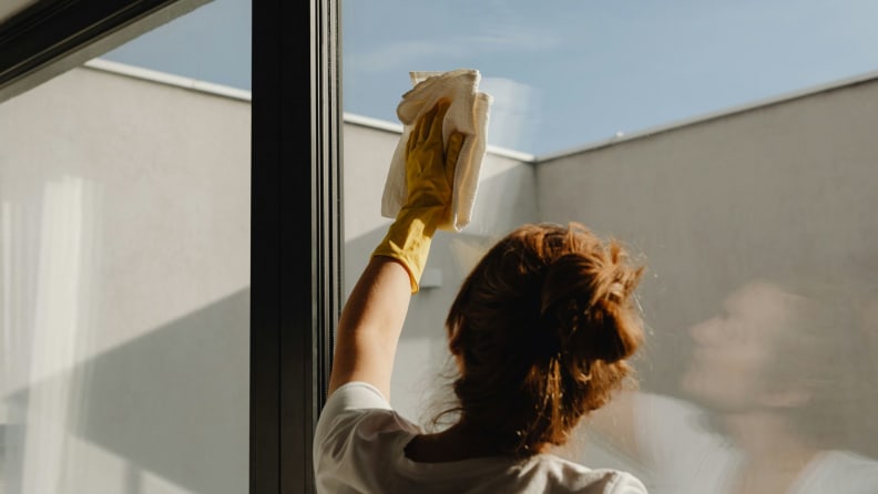 View from behind a woman wiping down a clear window.