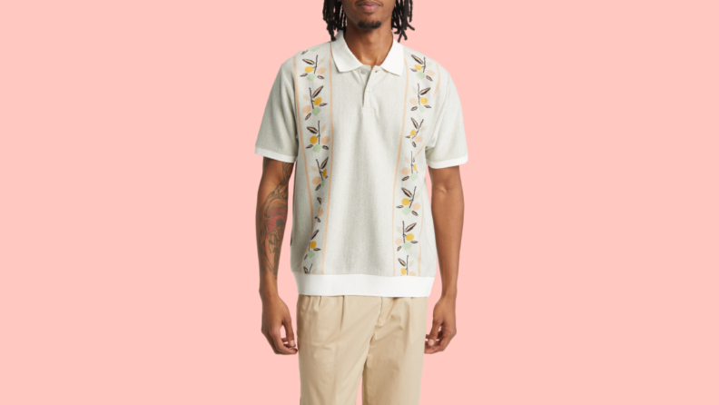 A man wears an off-white polo printed with a botanical print.