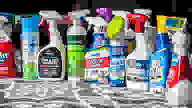 More than a dozen carpet stain cleaners displayed on a carpet.