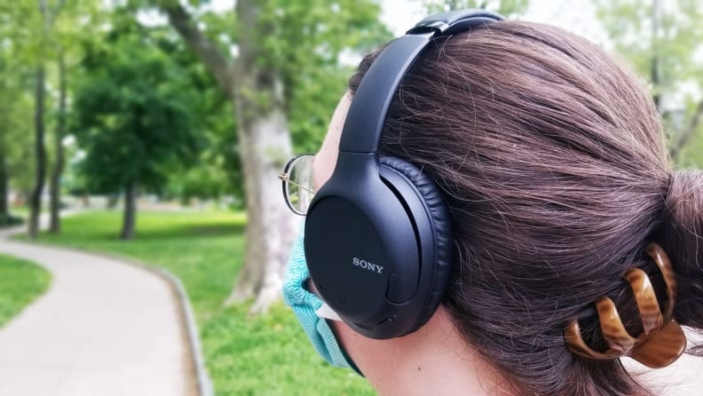 Back of man's head while he wears the Sony WH-CH710N travel headphones and face mask.