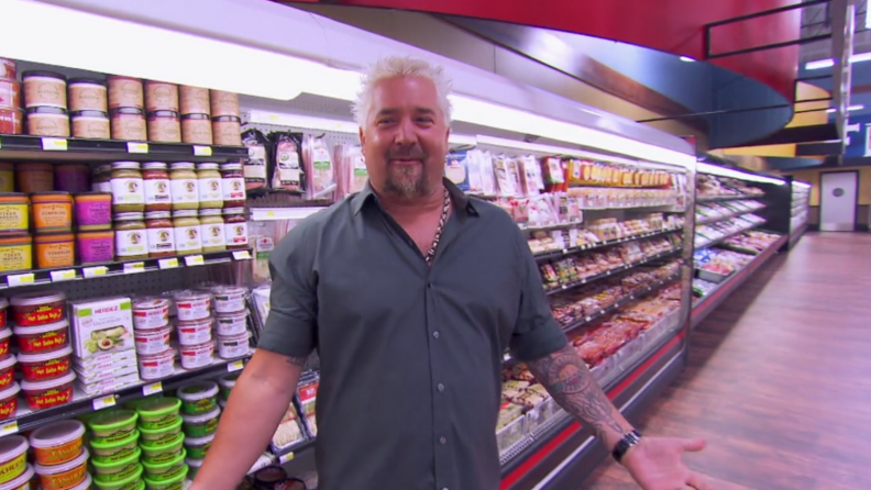 A still of Guy Fieri in the grocery aisles of Guy's Grocery Games.