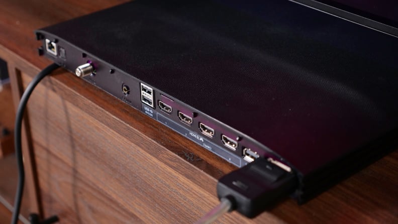 A closeup of the connection ports of the Samsung One Connect Box for the S95C sitting on a wooden credenza.