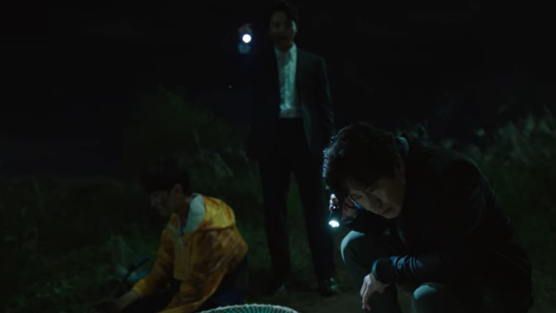 Men holding flashlight after discovering something shocking buried underground.