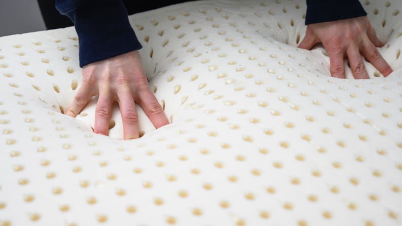 Hands press down on a foam mattress topper