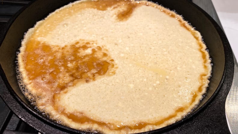 Batter for a Dutch baby begins to cook in a cast-iron skillet.