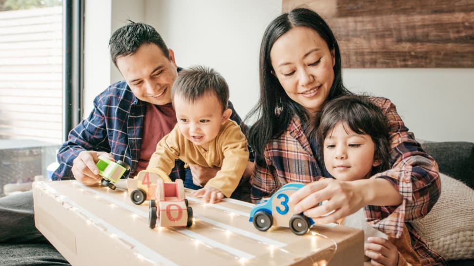 Family playing with toy cars in a living room.