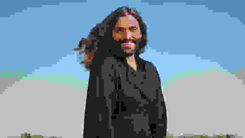 Jonathan Van Ness stands against a sky in the background.