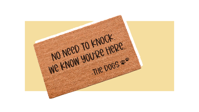 A brown doormat reading "No need to know. We know you're here - The Dogs" against a light gold background.