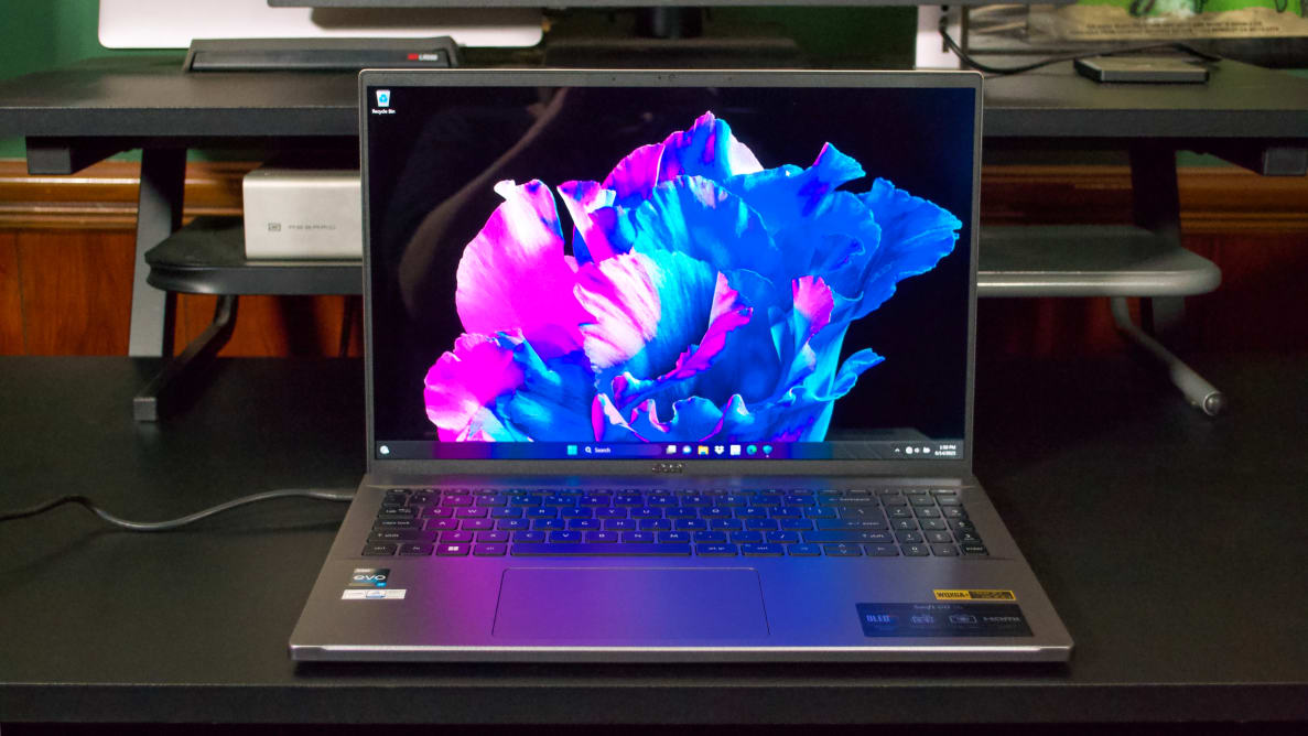 An open and powered on laptop showing a colorful neon pink and blue design on the screen
