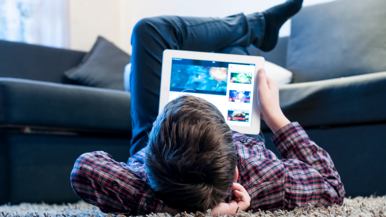 Teen laying on the floor using a tablet