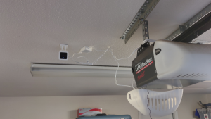 A security camera hangs next to a garage door opener