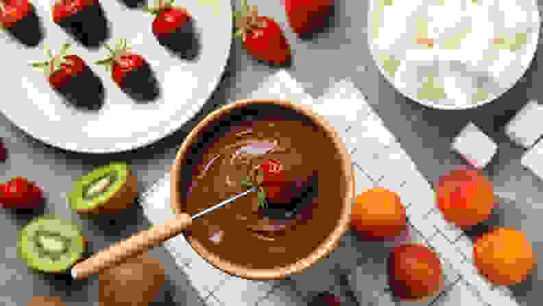 Composition with ingredients for chocolate fondue on gray table.