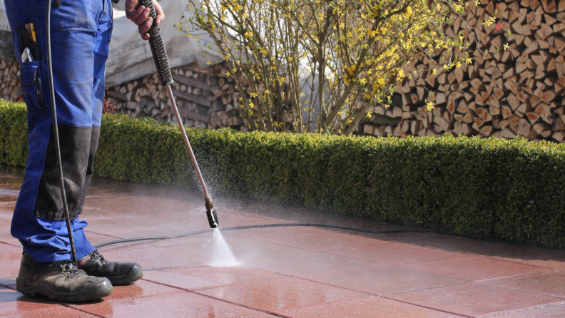 Person spraying down tile surface around yard