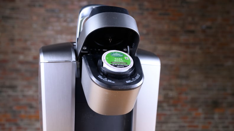 The Keurig coffee maker opened to reveal a capsule inserted inside.