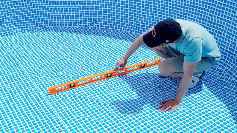 A person measures the base of the Intex above ground pool.