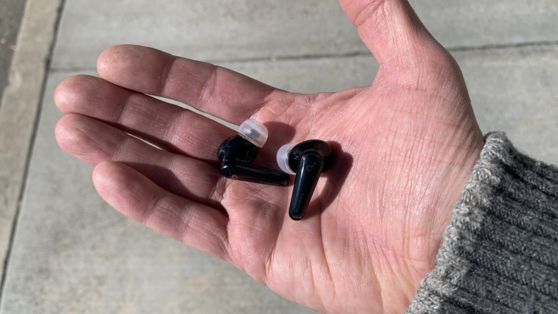 A Caucasian man's hand holding the Anker Soundcore Liberty 4 earbuds in his palm.