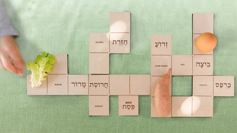 Child's hand putting lettuce on a wooden seder plate