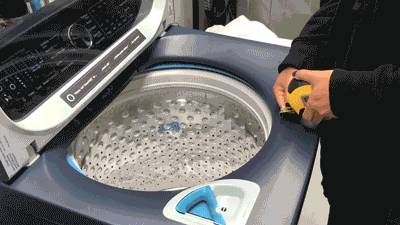 Moving gif of someone using a measuring tape to measure the depth of the drum inside of the GE Profile PTW900BPTRS washing machine.