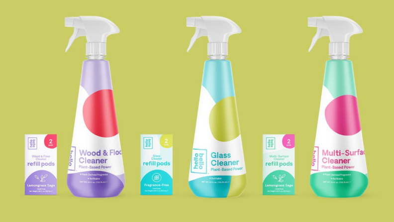 Product shot of multi-colored Hello Bello cleaning products in front of green background.