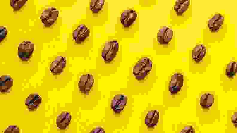 Coffee beans arranged in a pattern on a bright yellow surface.