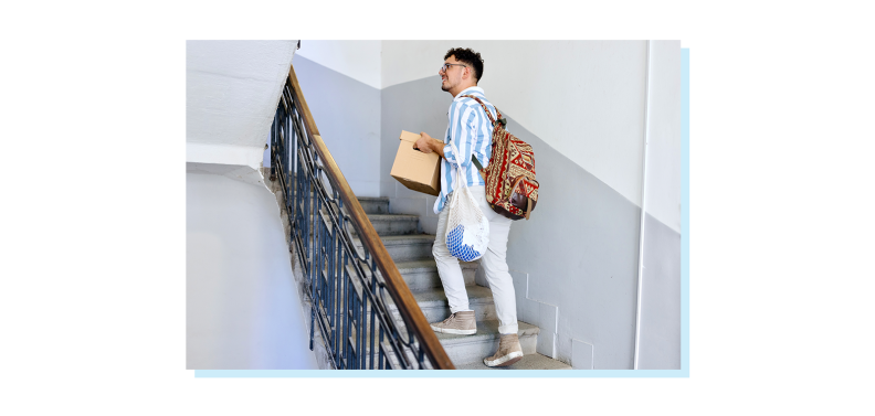 Person holding moving box while going up flight of stairs.