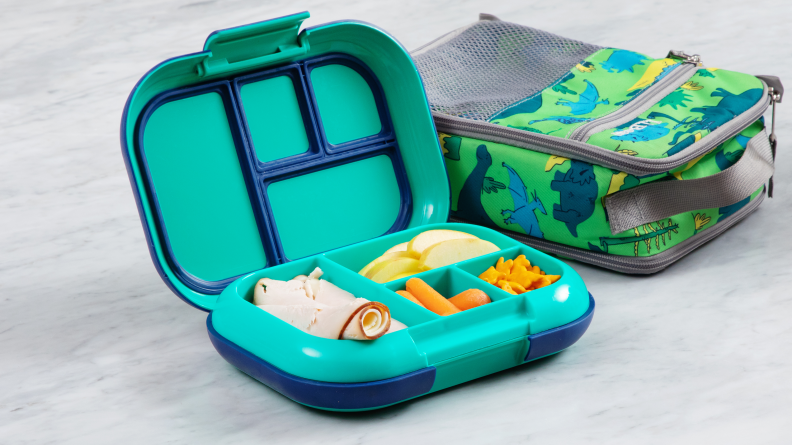The Bentgo Chill lunch box sits open on a marble counter and holds turkey, carrots, apples and cheddar bunnies. The LL Bean lunch box sits behind it.