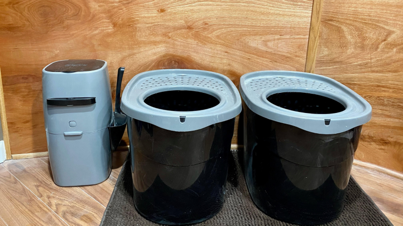 One Litter Genie pail next to two gray and black litter boxes.