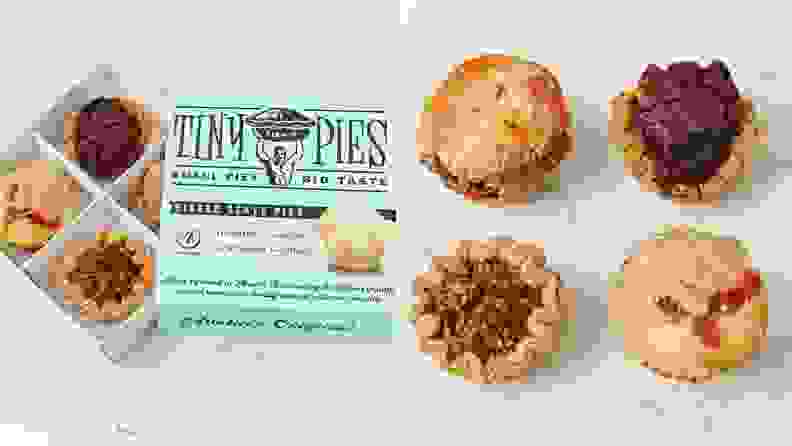 On left, Tiny Pies box opened on an angle revealing the pies. On right, all four flavors of Tiny Pies laid out on white marble countertop.