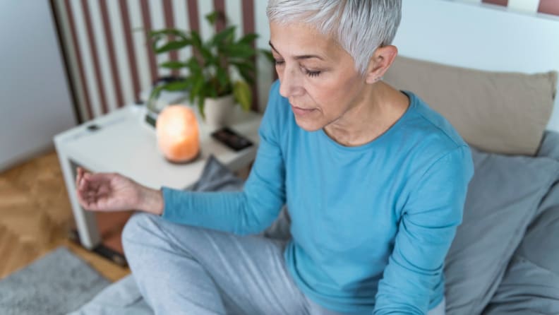 a person sits on their bed meditating